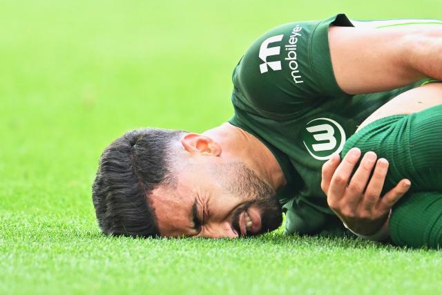 11 April 2026, Lower Saxony, Wolfsburg: Wolfsburg's Mohamed Amoura lies on the ground after sustaining an injury during the German Bundesliga soccer match between VfL Wolfsburg and Eintracht Frankfurt at the Volkswagen Arena. Photo: Swen Pförtner/dpa - IMPORTANT NOTICE: DFL and DFB regulations prohibit any use of photographs as image sequences and/or quasi-video.