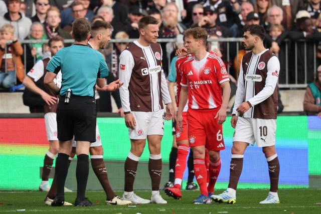 11 April 2026, Hamburg: Bayern Munich's Joshua Kimmich stands between FC St. Pauli's Hauke Wahl and Danel Sinani (R) and discusses the play with referee Tobias Stieler during the German Bundesliga soccer match between FC St. Pauli and Bayern Munich at Millerntor Stadium. Photo: Christian Charisius/dpa - IMPORTANT NOTICE: DFL and DFB regulations prohibit any use of photographs as image sequences and/or quasi-video.