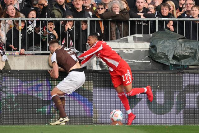 11 April 2026, Hamburg: St. Pauli's Karol Mets and Bayern Munich's Michael Olise (R) battle for the ball during the German Bundesliga soccer match between FC St. Pauli and Bayern Munich at Millerntor Stadium. Photo: Christian Charisius/dpa - IMPORTANT NOTICE: DFL and DFB regulations prohibit any use of photographs as image sequences and/or quasi-video.