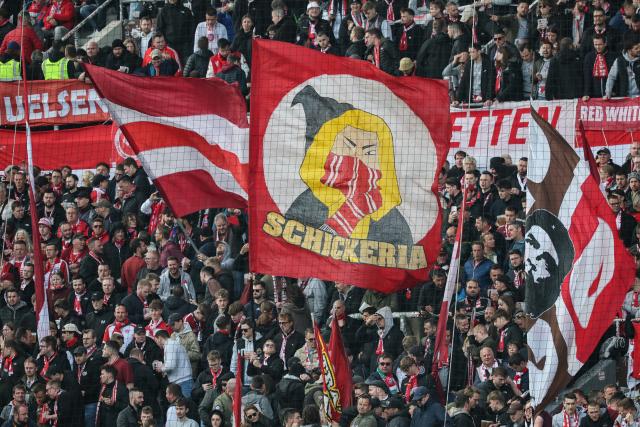 11 April 2026, Hamburg: Munich fans wave flags in the stands ahead of the German Bundesliga soccer match between FC St. Pauli and Bayern Munich at Millerntor Stadium. Photo: Christian Charisius/dpa - IMPORTANT NOTICE: DFL and DFB regulations prohibit any use of photographs as image sequences and/or quasi-video.