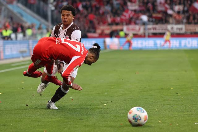 11 April 2026, Hamburg: Bayern Munich's Michael Olise and St. Pauli's Joel Chima Fujita battle for the ball during the German Bundesliga soccer match between FC St. Pauli and Bayern Munich at Millerntor Stadium. Photo: Christian Charisius/dpa - IMPORTANT NOTICE: DFL and DFB regulations prohibit any use of photographs as image sequences and/or quasi-video.