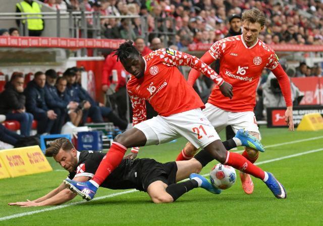 12 April 2026, Rhineland-Palatinate, Mainz: Mainz's Danny da Costa (C) and Stefan Posch battle for the ball with Freiburg's Lucas Hoeler during the German Bundesliga soccer match between FSV Mainz 05 and SC Freiburg at Mewa Arena. Photo: Torsten Silz/dpa - WICHTIGER HINWEIS: Gemäß den Vorgaben der DFL Deutsche Fußball Liga bzw. des DFB Deutscher Fußball-Bund ist es untersagt, in dem Stadion und/oder vom Spiel angefertigte Fotoaufnahmen in Form von Sequenzbildern und/oder videoähnlichen Fotostrecken zu verwerten bzw. verwerten zu lassen.