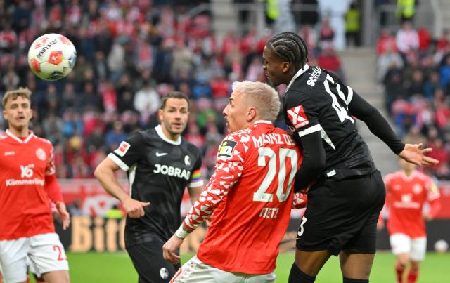 12 April 2026, Rhineland-Palatinate, Mainz: Mainz's Phillip Tietz (L) and Freiburg's Bruno Ogbus battle for the ball during the German Bundesliga soccer match between FSV Mainz 05 and SC Freiburg at Mewa Arena. Photo: Torsten Silz/dpa - WICHTIGER HINWEIS: Gemäß den Vorgaben der DFL Deutsche Fußball Liga bzw. des DFB Deutscher Fußball-Bund ist es untersagt, in dem Stadion und/oder vom Spiel angefertigte Fotoaufnahmen in Form von Sequenzbildern und/oder videoähnlichen Fotostrecken zu verwerten bzw. verwerten zu lassen.