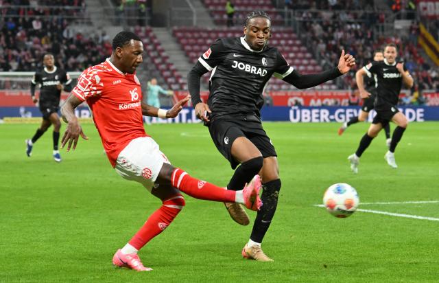 12 April 2026, Rhineland-Palatinate, Mainz: Freiburg's Bruno Ogbus (R) and Mainz's Sheraldo Becker battle for the ball during the German Bundesliga soccer match between FSV Mainz 05 and SC Freiburg at Mewa Arena. Photo: Torsten Silz/dpa - WICHTIGER HINWEIS: Gemäß den Vorgaben der DFL Deutsche Fußball Liga bzw. des DFB Deutscher Fußball-Bund ist es untersagt, in dem Stadion und/oder vom Spiel angefertigte Fotoaufnahmen in Form von Sequenzbildern und/oder videoähnlichen Fotostrecken zu verwerten bzw. verwerten zu lassen.
