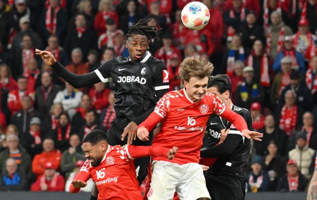 12 April 2026, Rhineland-Palatinate, Mainz: Mainz's Stefan Posch (R) and Freiburg's Johan Manzambi battle for the ball during the German Bundesliga soccer match between FSV Mainz 05 and SC Freiburg at Mewa Arena. Photo: Torsten Silz/dpa - WICHTIGER HINWEIS: Gemäß den Vorgaben der DFL Deutsche Fußball Liga bzw. des DFB Deutscher Fußball-Bund ist es untersagt, in dem Stadion und/oder vom Spiel angefertigte Fotoaufnahmen in Form von Sequenzbildern und/oder videoähnlichen Fotostrecken zu verwerten bzw. verwerten zu lassen.