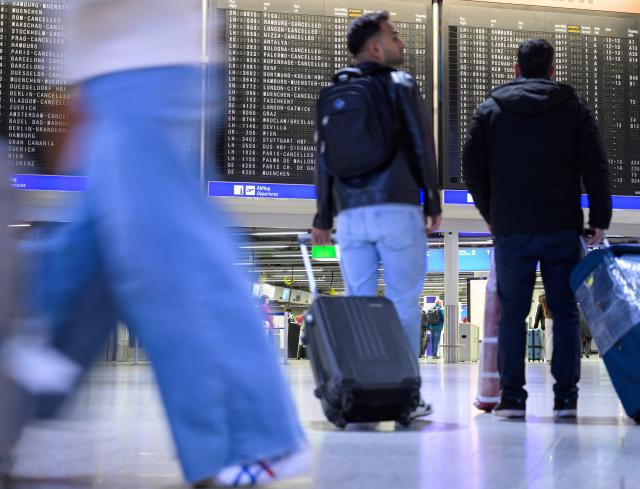 13 April 2026, Hesse, Frankfurt/Main: People stand in front of a display board with canceled Lufthansa flights at Frankfurt Airport. The Vereinigung Cockpit pilots' union has called for work stoppages at Lufthansa and several subsidiaries on Monday and Tuesday. Photo: Hannes P. Albert/dpa