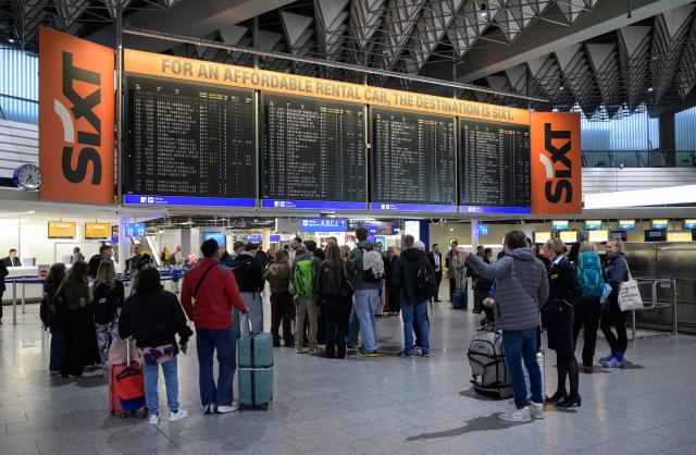 13 April 2026, Hesse, Frankfurt/Main: People stand in front of a display board with canceled Lufthansa flights at Frankfurt Airport. The Vereinigung Cockpit pilots' union has called for work stoppages at Lufthansa and several subsidiaries on Monday and Tuesday. Photo: Hannes P. Albert/dpa
