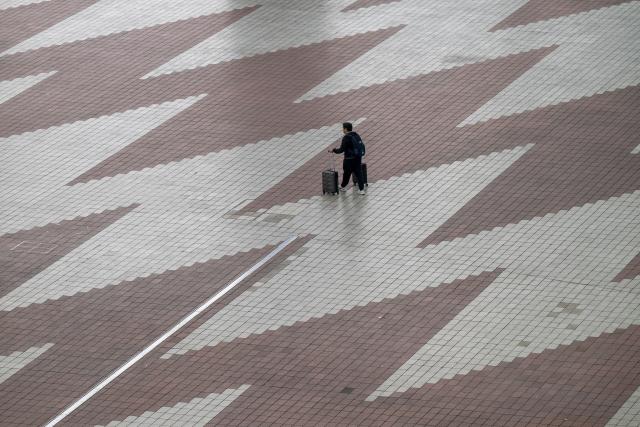 13 April 2026, Bavaria, Munich: A passer-by walks with his luggage to Munich Airport in the morning. The Vereinigung Cockpit pilots' union has called for work stoppages at Lufthansa and several subsidiaries on Monday and Tuesday. Photo: Peter Kneffel/dpa