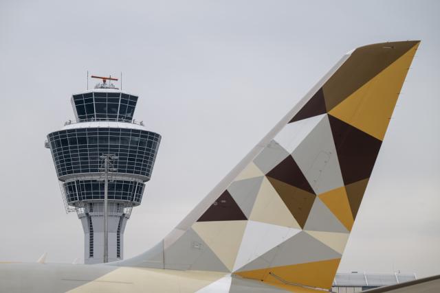 13 April 2026, Bavaria, Freising: An airplane passes the tower at Munich Airport. A new building will provide capacity for up to six million passengers per year. Photo: Peter Kneffel/dpa