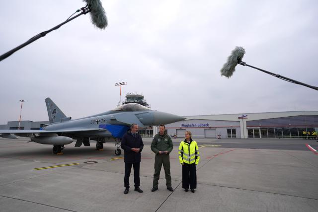 13 April 2026, Schleswig-Holstein, Lübeck: Colonel Dominique Gentzsch (C), Commodore of Tactical Air Force Wing 73 "Steinhoff", as well as Henning Schumann (L), Mayor of the Hanseatic City of Luebeck, and Stefanie Eggers (R), spokesperson for Luebeck Airport, speak to media representatives at Lübeck Airport in front of a Eurofighter fighter aircraft during the air force exercise "Dispersed Operations 2026". From April 13 to 17, the Tactical Air Force Wing 73 "Steinhoff" will be training take-offs and landings with military fighter aircraft. The aim of the "Dispersed Operations 2026" exercise is to strengthen cooperation with civilian institutions and to practice defense capabilities in a realistic alliance situation. Photo: Marcus Brandt/dpa
