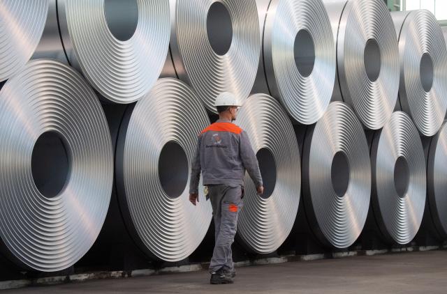 FILED - 12 July 2020, Lower Saxony, Salzgitter: An employee walks along coiled steel at Salzgitter AG. EU negotiators have agreed to tighten steel import rules, sharply reducing the volume that can enter the bloc duty-free in a bid to protect domestic producers. Photo: Julian Stratenschulte/dpa