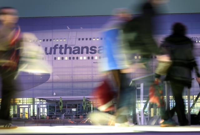 14 April 2026, Bavaria, Munich: People walk past a large image of a Lufthansa aircraft at Terminal 2 early in the morning on the second day of the pilots' strike. Photo: Karl-Josef Hildenbrand/dpa