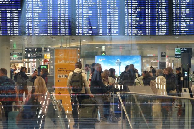 14 April 2026, Bavaria, Munich: People stand in front of a departure board in Terminal 2 early in the morning on the second day of the Lufthansa pilots' strike. Photo: Karl-Josef Hildenbrand/dpa