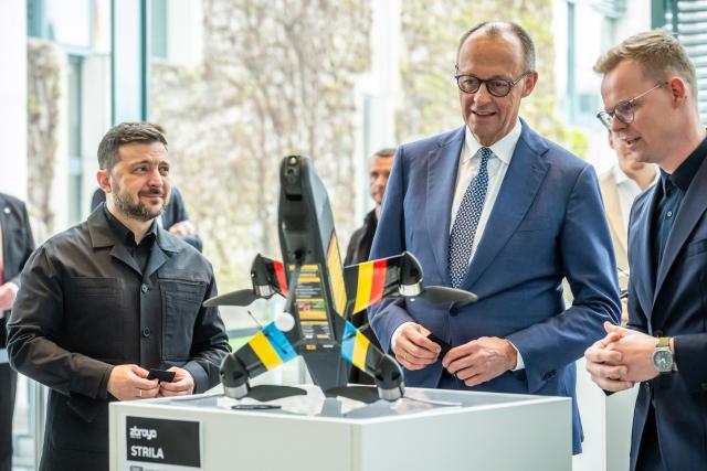 14 April 2026, Berlin: Friedrich Merz (C), Germany's Chancellor, inspects a Strila drone alongside Volodymyr Zelensky (L), President of Ukraine, at an exhibition of German-Ukrainian joint projects at the Federal Chancellery on the occasion of the German-Ukrainian government consultations. Photo: Michael Kappeler/dpa