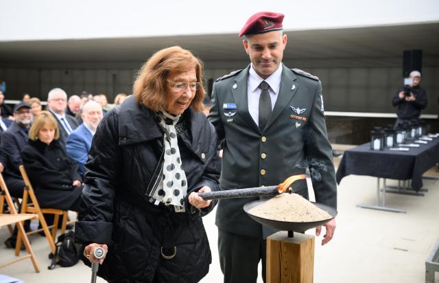 14 April 2026, Brandenburg, Oranienburg: Holocaust survivor Ingeburg Geissler (L) lights the commemorative torch alongside Colonel Aviran Lerer, defense attaché at the Israeli Embassy, during a commemorative event marking Yom HaShoah, Israel's Holocaust Remembrance Day, at the Sachsenhausen Memorial. Between 1936 and 1945, more than 200,000 people were imprisoned at the Sachsenhausen concentration camp. Tens of thousands of them lost their lives there. Photo: Bernd von Jutrczenka/dpa