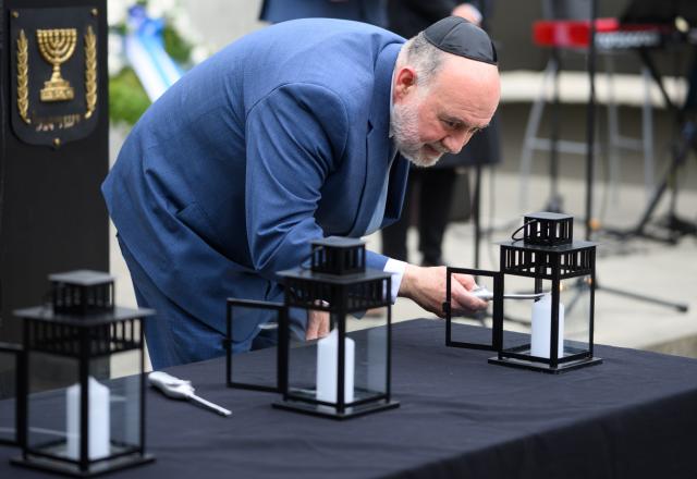 14 April 2026, Brandenburg, Oranienburg: Ron Prosor, Israel's ambassador to Germany, lights a candle at a commemorative event marking Yom HaShoah, Israel's Holocaust Remembrance Day, at the Sachsenhausen Memorial. Between 1936 and 1945, more than 200,000 people were imprisoned at the Sachsenhausen concentration camp. Tens of thousands of them lost their lives there. Photo: Bernd von Jutrczenka/dpa