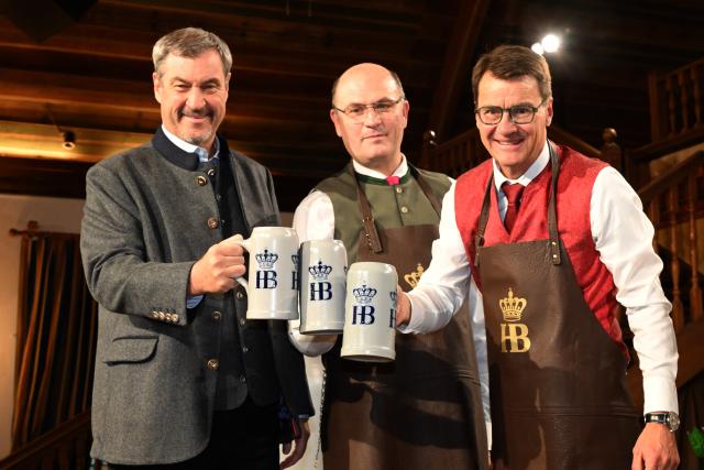 14 April 2026, Bavaria, Munich: Markus Soeder, Prime Minister of Bavaria,  Albert Fueracker and Joerg Lehmann, Director of the Staatliches Hofbrauhaus, stand on the stage during the 2026 Maibock tapping ceremony in the Hofbraeuhaus ballroom. Photo: Felix Hörhager/dpa