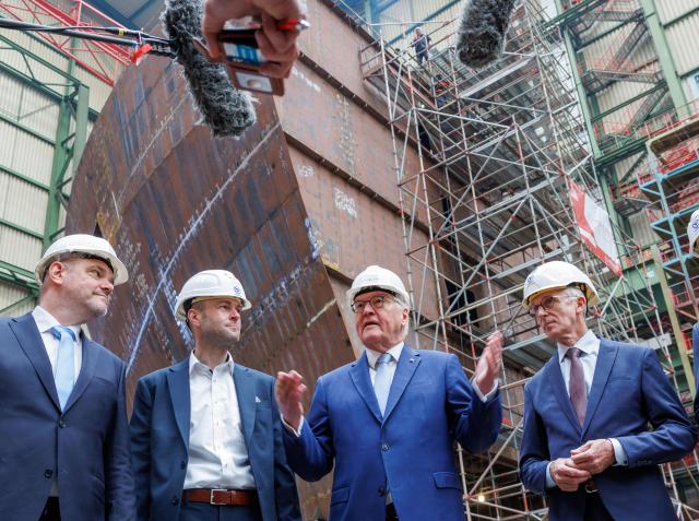 15 April 2026, Mecklenburg-Western Pomerania, Stralsund: German President Frank-Walter Steinmeier (C) speaks to members of the press in front of a bow section of a new ship under construction during a visit to the Fassmer company at the Volkswerft shipyard. As part of his "Local Time Germany" series of visits, the Federal President is moving his official residence to Stralsund until 16.04.2026. Photo: Jens Büttner/dpa