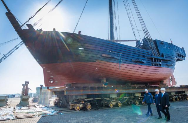 15 April 2026, Mecklenburg-Western Pomerania, Stralsund: German President Frank-Walter Steinmeier (M) walks past the replica of the cog "Wisemara" with Peter Fürst (l), Head of the Office for Economic Development and City Marketing in Stralsund, and Alexander Badrow (r, CDU), Mayor of the Hanseatic City of Stralsund, on the Volkswerft industrial estate. The wooden ship is being repaired in the shipyard. As part of his "Local Time Germany" series of visits, the Federal President is moving his official residence to Stralsund until 16.04.2026. Photo: Jens Büttner/dpa