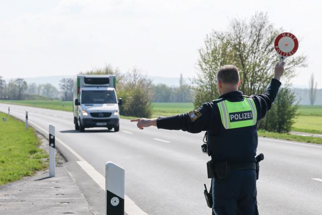 15 April 2026, Bavaria, Sulzheim-Alitzheim: A police officer from Gerolzhofen police station waves a small truck out of a parking lot on the B286 with a police trowel during the Bavaria-wide speed camera marathon. Photo: Daniel Löb/dpa
