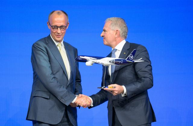 15 April 2026, Hesse, Frankfurt/Main: Carsten Spohr (R), Chairman of the Executive Board and CEO of Lufthansa, hands over a model aircraft to German Chancellor Friedrich Merz on stage at a ceremony marking the 100th anniversary of Lufthansa AG. Photo: Hannes P. Albert/dpa