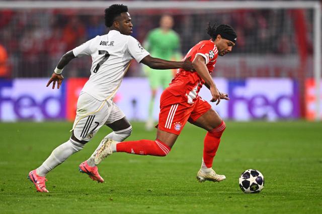 15 April 2026, Bavaria, Munich: Real Madrid's Vinicius Junior (L) and Bayern Munich's Serge Gnabry battle for the ball during the UEFA Champions League Quarterfinal Second Leg soccer match between Bayern Munich and Real Madrid at Allianz Arena. Photo: Tom Weller/dpa