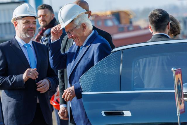 16 April 2026, Mecklenburg-Western Pomerania, Stralsund: German President Frank-Walter Steinmeier (C) puts on a hard hat as he greeted by mayor of the Hanseatic City of Stralsund Alexander Badrow (L) during a visit to the Volkswerft industrial area, as part of his "Local Time Germany" tour. Photo: Jens Büttner/dpa