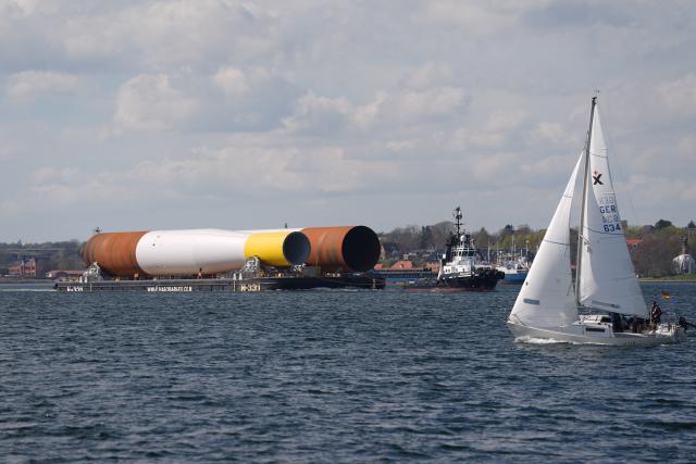 16 April 2026, Schleswig-Holstein, Kiel: Tugs are towing a barge carrying parts of an offshore wind turbine on the Kiel Fjord. Photo: Marcus Brandt/dpa