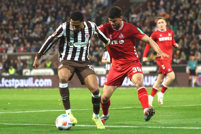 17 April 2026, Hamburg: Cologne's  Cenk Oezkacar (R) and St. Pauli's Andreas Hountondji battle for the ball during the German Bundesliga soccer match between FC St. Pauli and 1. FC Cologne at Millerntor Stadium. Photo: Christian Charisius/dpa - WICHTIGER HINWEIS: Gemäß den Vorgaben der DFL Deutsche Fußball Liga bzw. des DFB Deutscher Fußball-Bund ist es untersagt, in dem Stadion und/oder vom Spiel angefertigte Fotoaufnahmen in Form von Sequenzbildern und/oder videoähnlichen Fotostrecken zu verwerten bzw. verwerten zu lassen.