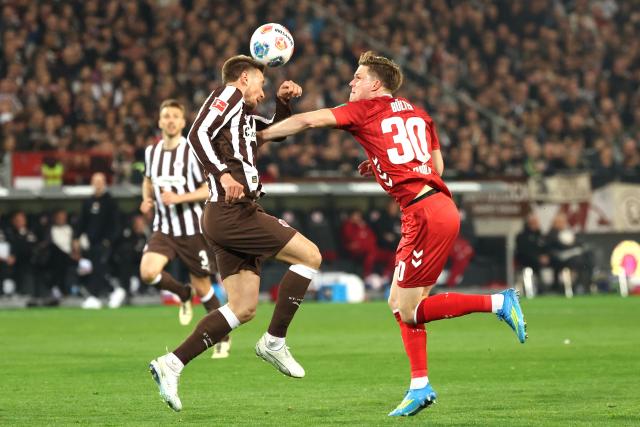 17 April 2026, Hamburg: Cologne's Marius Buelter (R) and St. Pauli's James Sands battle for the ball during the German Bundesliga soccer match between FC St. Pauli and 1. FC Cologne at Millerntor Stadium. Photo: Christian Charisius/dpa - WICHTIGER HINWEIS: Gemäß den Vorgaben der DFL Deutsche Fußball Liga bzw. des DFB Deutscher Fußball-Bund ist es untersagt, in dem Stadion und/oder vom Spiel angefertigte Fotoaufnahmen in Form von Sequenzbildern und/oder videoähnlichen Fotostrecken zu verwerten bzw. verwerten zu lassen.