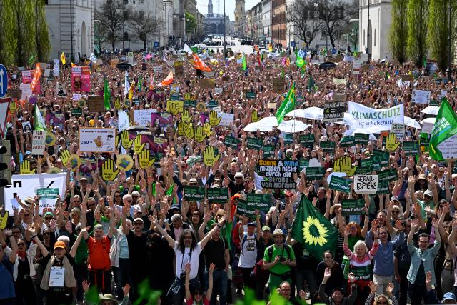 18 April 2026, Bavaria, Munich: Demonstrators raise their hands in front of the Siegestor during the demonstration under the slogan "Defend renewable energies". The demonstration is organized by Bund Naturschutz in Bayern, Fridays For Future Munich, Greenpeace Bayern and the Umweltinstitut München. Photo: Felix Hörhager/dpa
