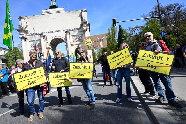18 April 2026, Bavaria, Munich: Demonstrators stand with signs reading "Future, gas (crossed out)" at the Siegestor during the demonstration under the motto "Defend renewable energies". The demonstration is organized by Bund Naturschutz in Bayern, Fridays For Future Munich, Greenpeace Bayern and the Umweltinstitut München. Photo: Felix Hörhager/dpa
