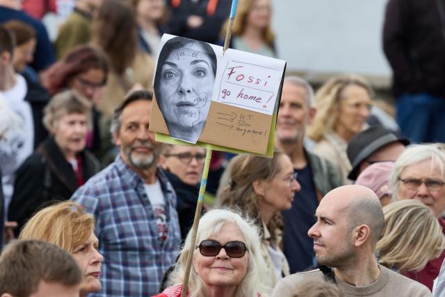 18 April 2026, Hamburg: A participant in a demonstration for the energy transition holds a banner with the words "Fossi go home!" with the portrait of the Federal Minister for Economic Affairs and Energy, Reiche, on the Lombardsbrücke. Campact, Deutsche Umwelthilfe, the Citizens' Energy Alliance, Greenpeace, WWF, Paritätische, Germanzero, Germanwatch and Fridays for Future called for protests across Germany. Photo: Georg Wendt/dpa