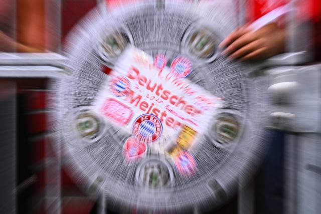 19 April 2026, Bavaria, Munich: Fan holds a sign shaped like the German Bundesliga championship trophy ahead of the German Bundesliga soccer match between Bayern Munich and VfB Stuttgart at Allianz Arena. Photo: Tom Weller/dpa - IMPORTANT NOTICE: DFL and DFB regulations prohibit any use of photographs as image sequences and/or quasi-video.