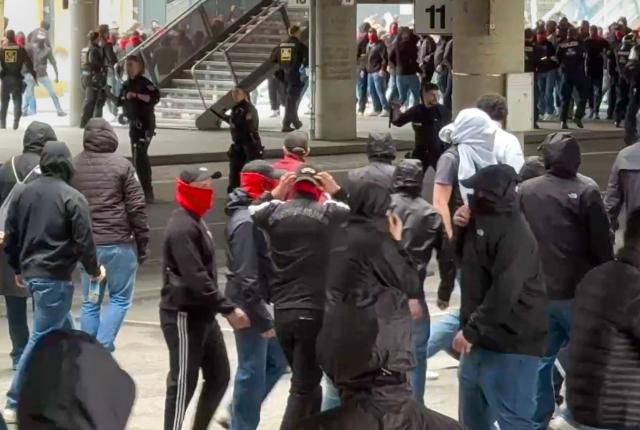 19 April 2026, Bavaria, Munich: Police officers (Back row, Center) are taking action against masked, violent fans ahead of the German Bundesliga soccer match between Bayern Munich and VfB Stuttgart at the Allianz Arena. Photo: -/EinsatzReport24/dpa - IMPORTANT NOTICE: DFL and DFB regulations prohibit any use of photographs as image sequences and/or quasi-video.