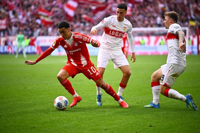19 April 2026, Bavaria, Munich: Bayern Munich's Jamal Musiala (L) battles for the ball with Stuttgart's Bilal El Khannouss (C) and Stuttgart's Finn Jeltsch (R) during the German Bundesliga soccer match between Bayern Munich and VfB Stuttgart at the Allianz Arena. Photo: Tom Weller/dpa - IMPORTANT NOTICE: DFL and DFB regulations prohibit any use of photographs as image sequences and/or quasi-video.