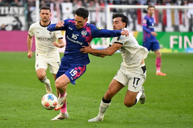 19 April 2026, North Rhine-Westphalia, Moenchengladbach: (L-R) Mainz's Anthony Caci and Borussia Moenchengladbach's Jens Castrop battle for the ball during the German Bundesliga soccer match between Borussia Moenchengladbach and FSV Mainz 05 at Borussia-Park Stadium. Photo: Ulrich Hufnagel/dpa - WICHTIGER HINWEIS: Gemäß den Vorgaben der DFL Deutsche Fußball Liga bzw. des DFB Deutscher Fußball-Bund ist es untersagt, in dem Stadion und/oder vom Spiel angefertigte Fotoaufnahmen in Form von Sequenzbildern und/oder videoähnlichen Fotostrecken zu verwerten bzw. verwerten zu lassen.