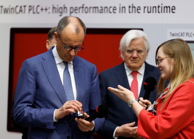 20 April 2026, Lower Saxony, Hanover: German Chancellor Friedrich Merz stands next to Hans Beckhoff (C), founder, CEO and shareholder of the technology company Beckhoff Automation, and looks at an industrial computer during the opening tour of the Hannover Messe. Brazil is the partner country at this year's Hannover Messe. Photo: Michael Matthey/dpa