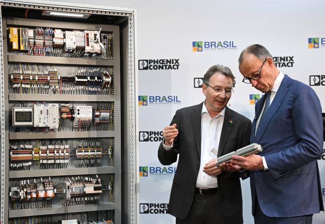 20 April 2026, Lower Saxony, Hanover: German Chancellor Friedrich Merz  stands at a switch box with Dirk Goerlitzer, CEO of Phoenix Contact, during the opening tour of the Hannover Messe. Brazil is the partner country at this year's Hannover Messe. Photo: Julian Stratenschulte/dpa