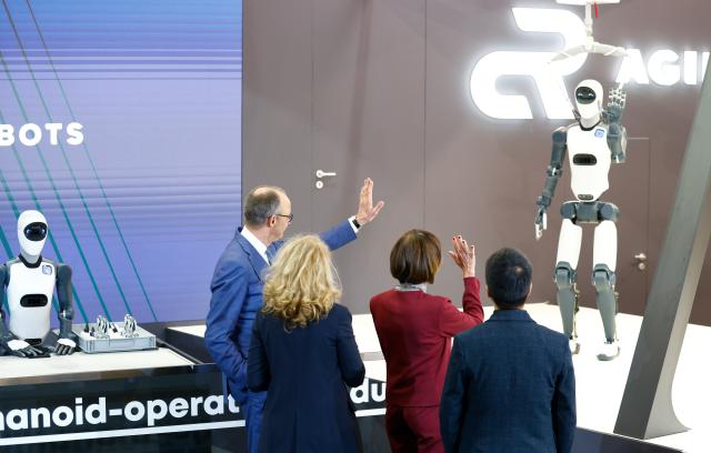 20 April 2026, Lower Saxony, Hanover: German Chancellor Friedrich Merz (L) stands with his wife Charlotte Merz (2nd R) at the Agile Robots stand during the opening tour of the Hannover Messe. Brazil is the partner country at this year's Hannover Messe. Photo: Michael Matthey/dpa