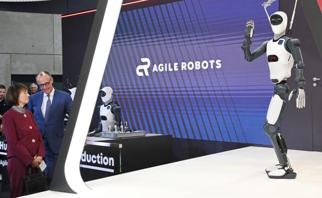 20 April 2026, Lower Saxony, Hanover: German Chancellor Friedrich Merz stands with his wife Charlotte Merz at the Agile Robots stand during the opening tour of the Hannover Messe. Brazil is the partner country at this year's Hannover Messe. Photo: Julian Stratenschulte/dpa