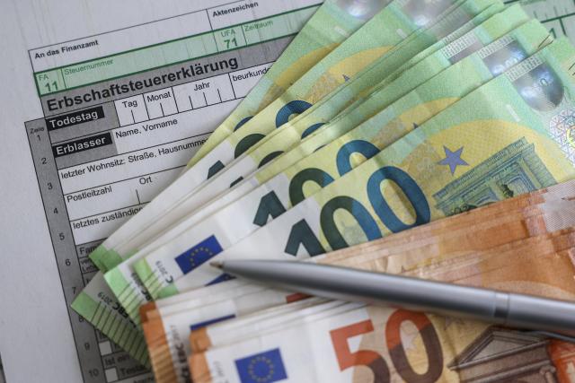 FILED - 13 January 2026, Saxony, Leipzig: There are banknotes of 100 and 50 euros on an inheritance tax return form. Photo: Jan Woitas/dpa
