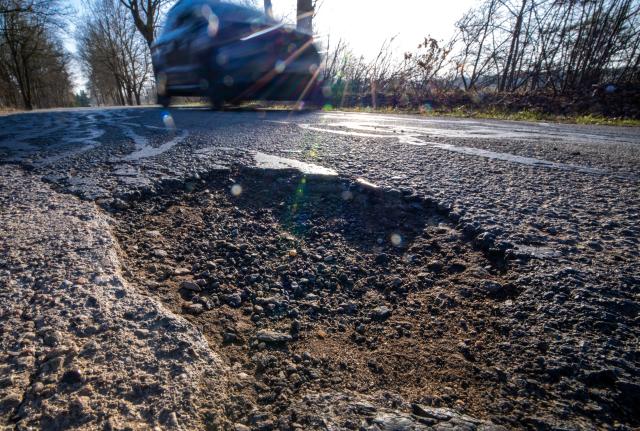 FILED - 09 March 2026, Mecklenburg-Western Pomerania, Lützow: A car drives past a pothole in a district road. Photo: Jens Büttner/dpa