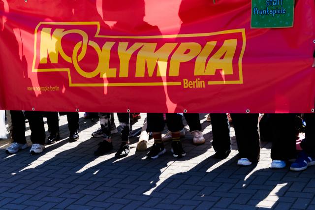 22 April 2026, Berlin: People are protesting against Berlin's planned bid for the Olympic Games, holding a banner that reads "No Olympics." The NOlympia Berlin coalition has officially begun collecting signatures for the referendum "For Berlin - Against the Olympics. We say no to a bid for the Olympic Games in 2036, 2040, and 2044!" Photo: Carsten Koall/dpa