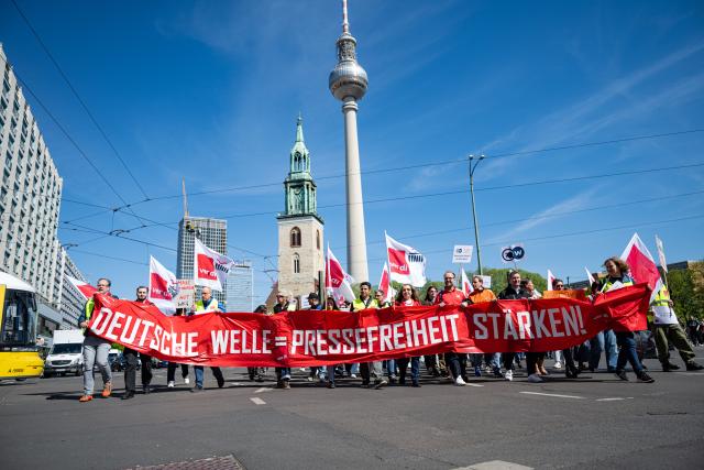 22 April 2026, Berlin: People carry a large banner reading " "Deutsche Welle = Strengthen freedom of the press" during a demonstration by the Deutsche Welle action alliance in Berlin. The motto of the demonstration is "Strengthen Deutsche Welle! For dialog and media freedom - worldwide!". Photo: Fabian Sommer/dpa