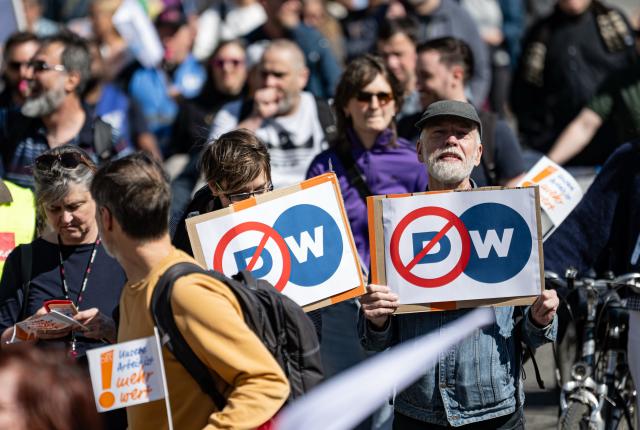 22 April 2026, Berlin: People carry signs during a demonstration by the Deutsche Welle action alliance in Berlin. The motto of the demonstration is "Strengthen Deutsche Welle! For dialog and media freedom - worldwide!". Photo: Fabian Sommer/dpa