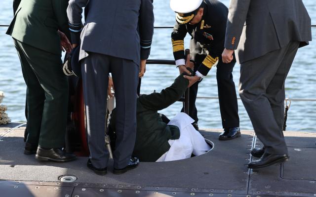 22 April 2026, Schleswig-Holstein, Kiel: Rajnath Singh (C), India's Defence Minister, stumbles while descending a ladder at submarine manufacturer Thyssenkrupp Marine Systems (TKMS) and is helped up by bystanders during a visit with Germany's Defence Minister Boris Pistorius. Photo: Christian Charisius/dpa