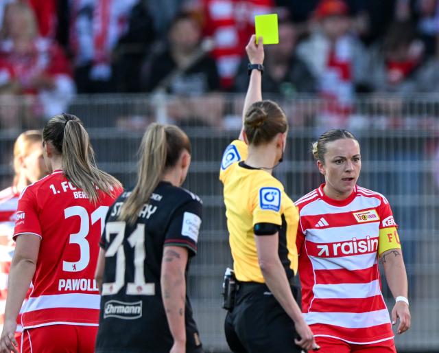 22 April 2026, Berlin: Referee Davina Lutz shows Union Berlin's Lisa Heiseler (R) a yellow card during the German Women's Bundesliga soccer match between 1. FC Union Berlin and Bayern Munich at the Old Forester's House Stadium. Photo: Soeren Stache/dpa - WICHTIGER HINWEIS: Gemäß den Vorgaben der DFL Deutsche Fußball Liga bzw. des DFB Deutscher Fußball-Bund ist es untersagt, in dem Stadion und/oder vom Spiel angefertigte Fotoaufnahmen in Form von Sequenzbildern und/oder videoähnlichen Fotostrecken zu verwerten bzw. verwerten zu lassen.