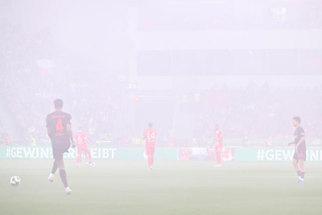 22 April 2026, North Rhine-Westphalia, Leverkusen: Bayer Leverkusen and Bayern Munich players stand amid thick smoke from pyrotechnics during the German DFB Cup semifinal soccer match between Bayer Leverkusen and Bayern Munich at BayArena. Photo: Federico Gambarini/dpa - IMPORTANT NOTICE: DFL and DFB regulations prohibit any use of photographs as image sequences and/or quasi-video.