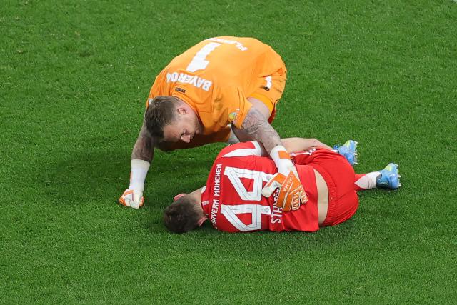 22 April 2026, North Rhine-Westphalia, Leverkusen: Bayer Leverkusen goalkeeper Mark Flekken checks on Bayern Munich's Josip Stanisic, who is lying injured on the ground during the German DFB Cup semifinal soccer match between Bayer Leverkusen and Bayern Munich at BayArena. Photo: Rolf Vennenbernd/dpa - IMPORTANT NOTICE: DFL and DFB regulations prohibit any use of photographs as image sequences and/or quasi-video.
